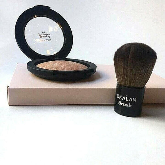 Open compact with a baked powder illuminator and an Okalan brush set on a light-colored box, perfect for a soft glow finish.