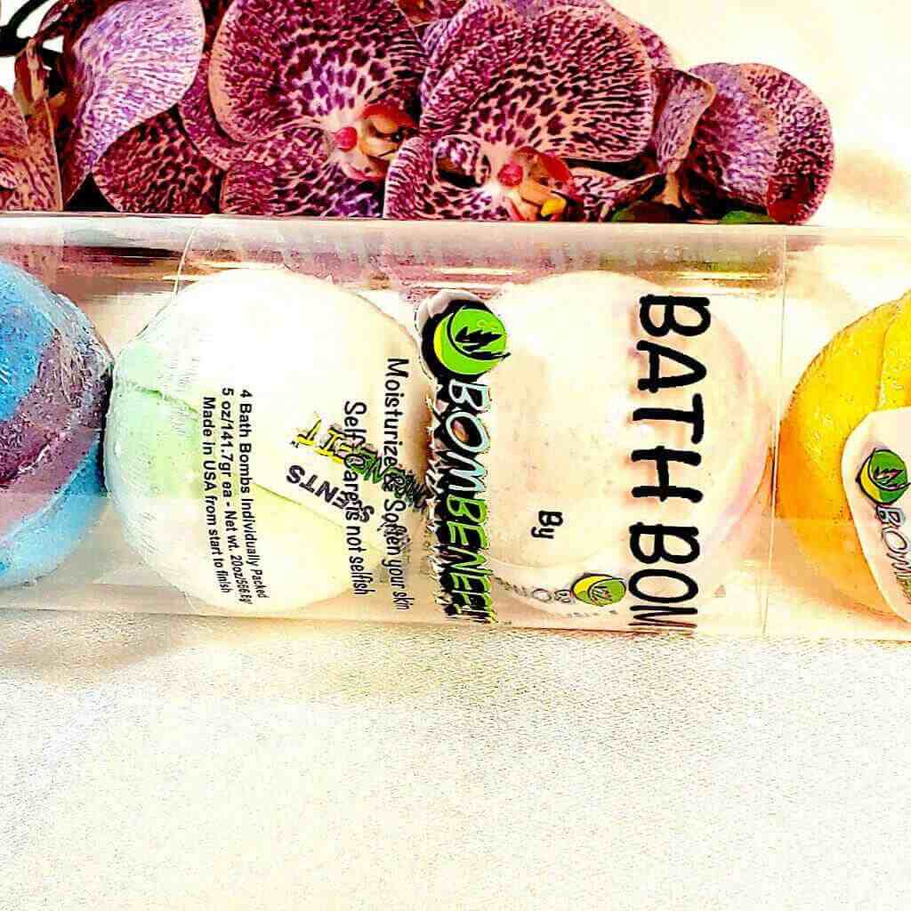 Bombenefit bath bombs in clear packaging with Milky Way and Sweet Peach scents, displayed against a vibrant orchid backdrop.
