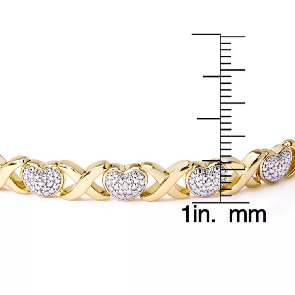 A gold bracelet with heart-shaped silver accents encrusted with small stones, shown next to a measurement scale in inches and mm.