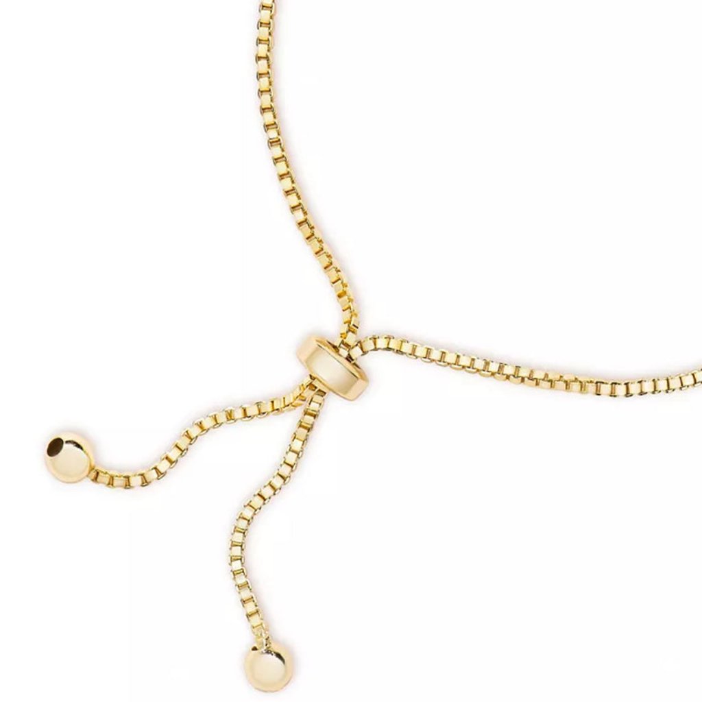 A close-up view of an adjustable gold bracelet with a box chain design, featuring a sliding clasp and two rounded end beads."