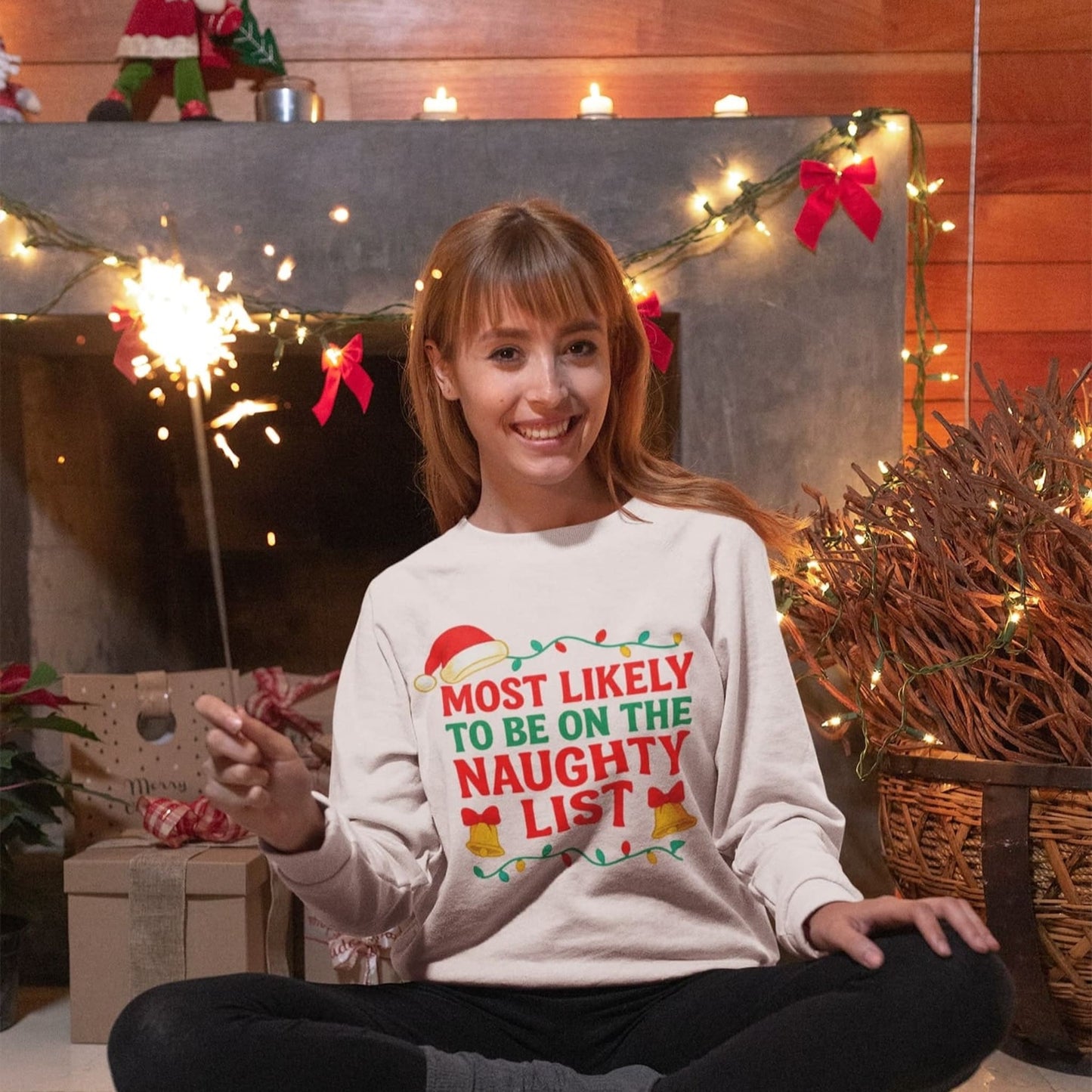 Woman celebrating Christmas wearing Gildan 18000 White sweatshirt with “Most Likely to Be on the Naughty List” design, funny unisex holiday sweater gift.