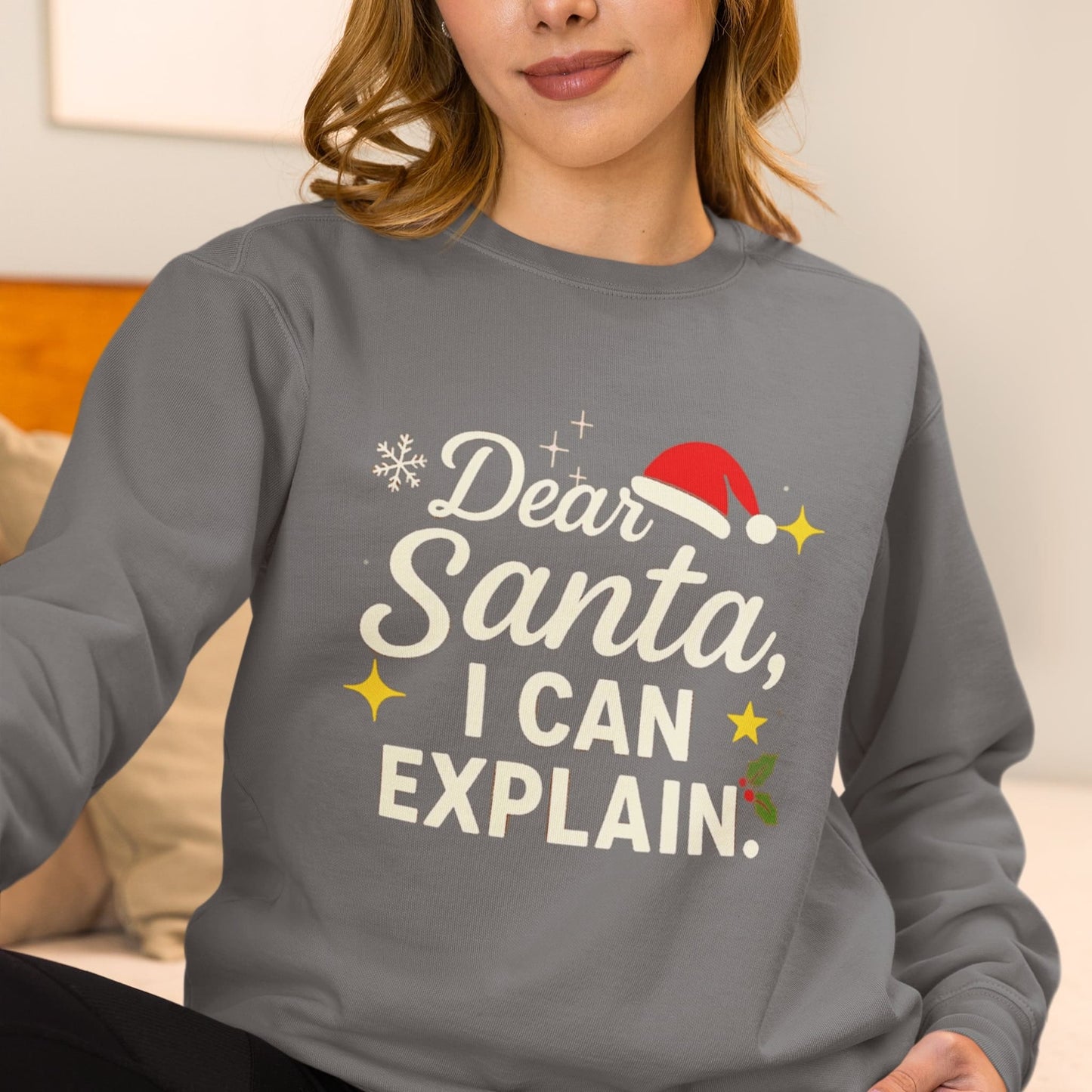 Woman wearing a grey sweatshirt with the festive text “Dear Santa, I Can Explain” featuring a Santa hat, snowflake, stars, and holly design.