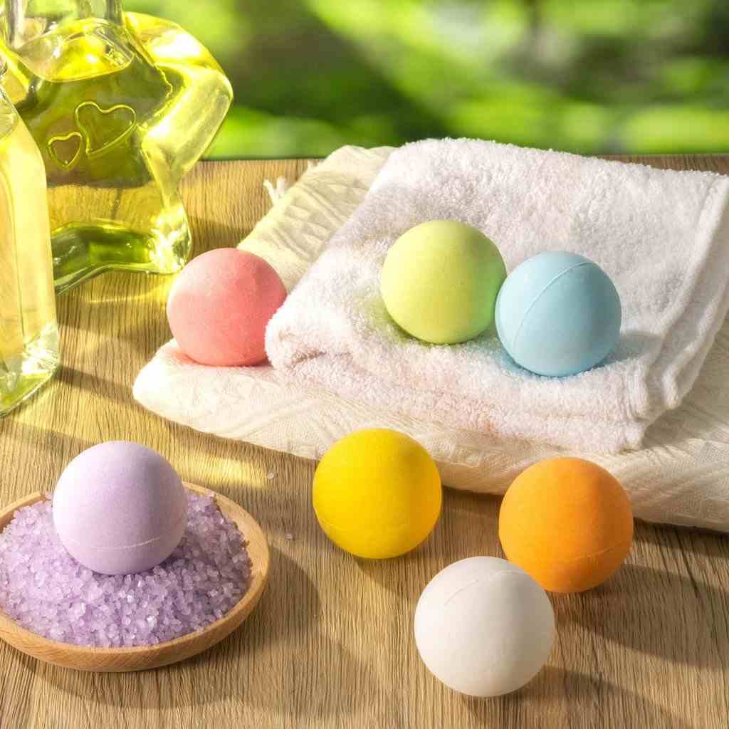 Colorful bath bombs on a towel and wood surface, paired with a glass bottle and lavender bath salts for a relaxing spa vibe.