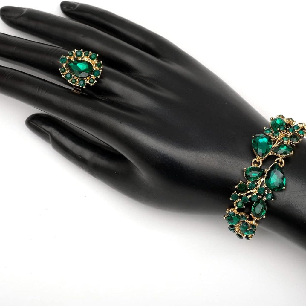 Emerald green crystal jewelry set with necklace, earrings, bracelet, and ring on gold accents, perfect for formal occasions or gifts.