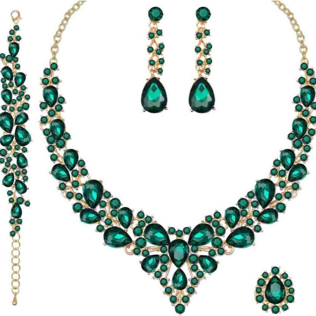 Elegant emerald green crystal jewelry set including a necklace, matching bracelet, drop earrings, and a gold-accented ring.