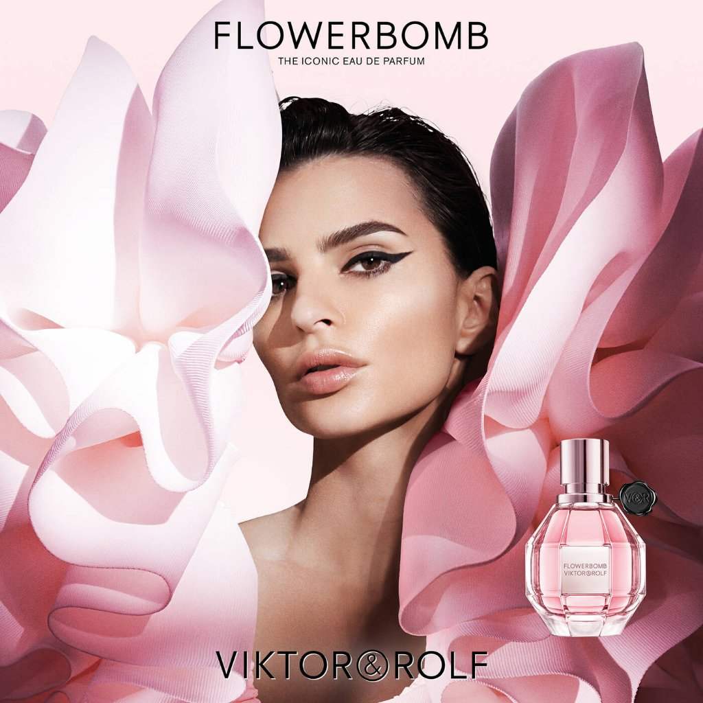 Model with bold eyeliner poses with pink floral fabric, showcasing Viktor & Rolf's Flowerbomb in a pink diamond-shaped bottle.