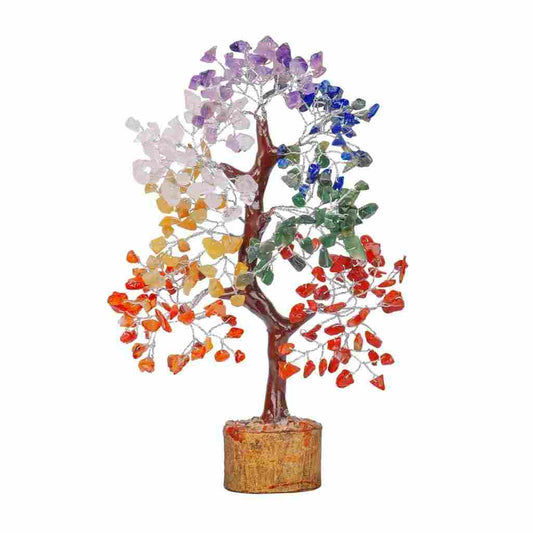 A decorative gemstone tree with multicolored crystal leaves representing the chakras, placed on a wooden base.