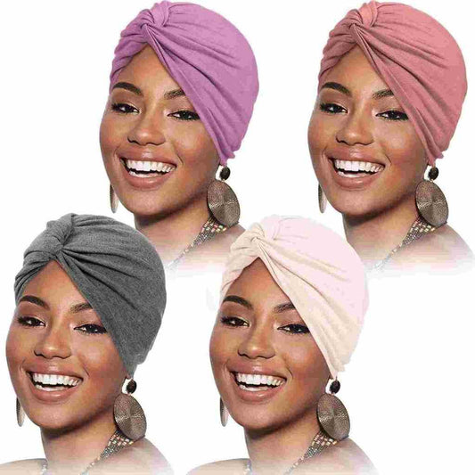 Smiling woman showcases four colorful retro-style turbans in shades of purple, pink, gray, and cream, paired with round earrings.