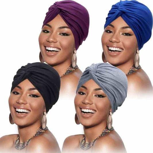 
Smiling woman models four vibrant twisted knot turbans in purple, blue, black, and gray, highlighting her chic style.