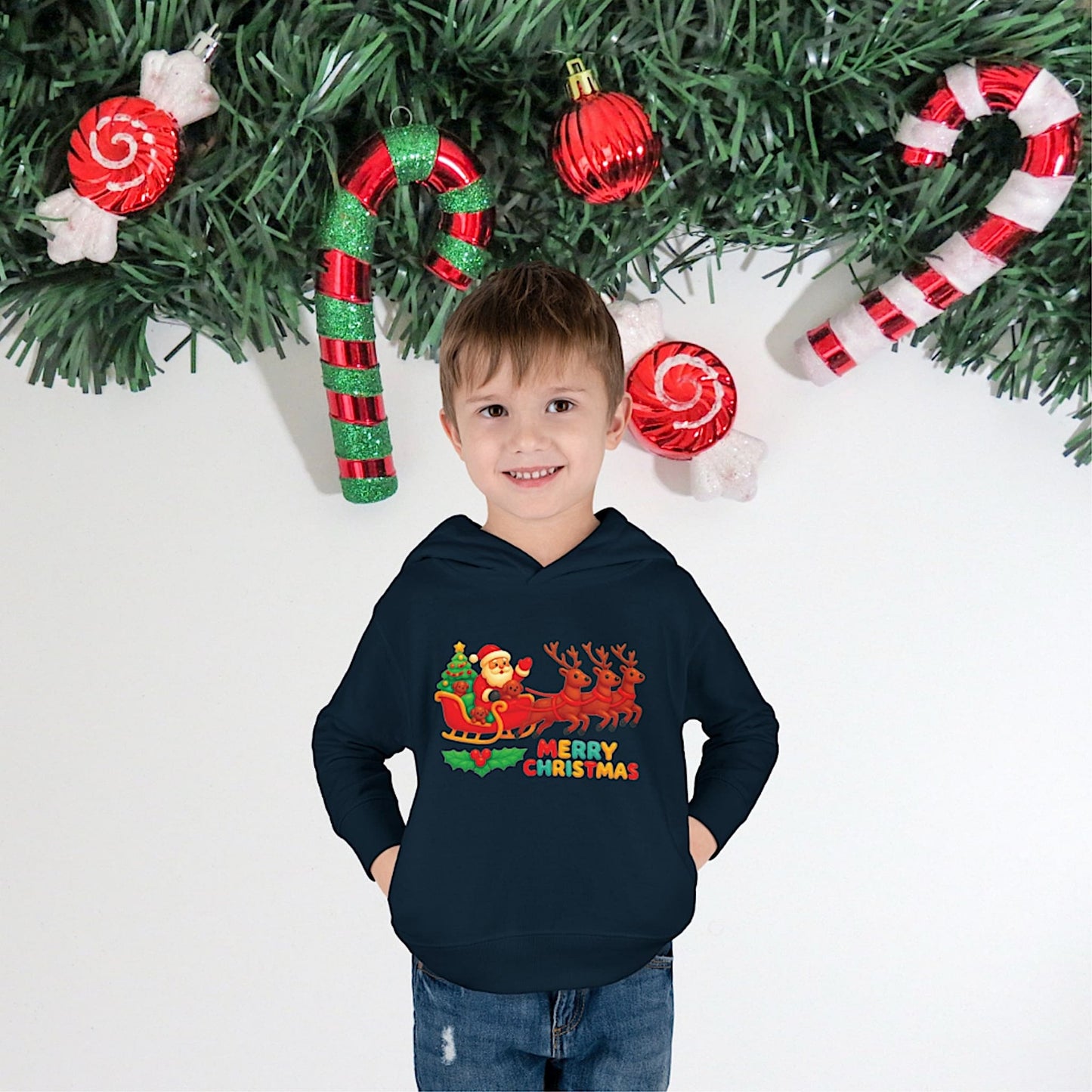 Boy wearing navy Christmas hoodie with Santa and reindeer sleigh design, festive holiday outfit.