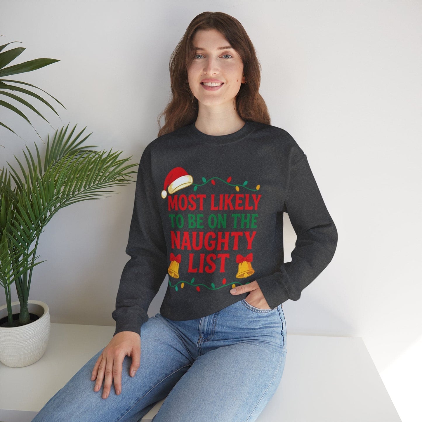 Woman wearing Gildan 18000 Dark Heather funny Christmas sweatshirt with “Most Likely to Be on the Naughty List” design, unisex holiday sweater gift.