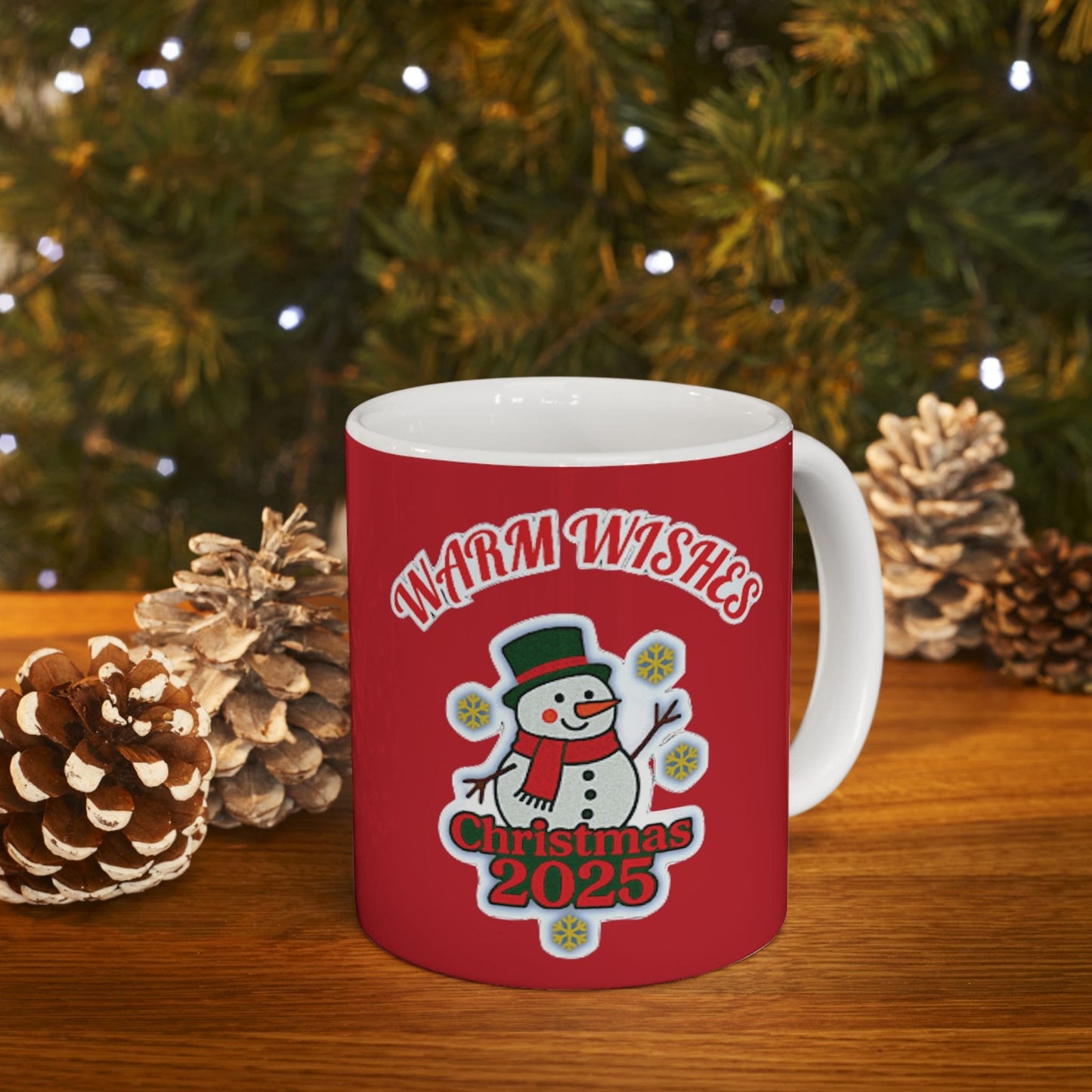 Red Christmas mug with snowman and 'Warm Wishes 2025' text, holiday gift with pinecones and festive lights.